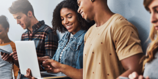 Young men and women gather around a computer screen talking and smiling